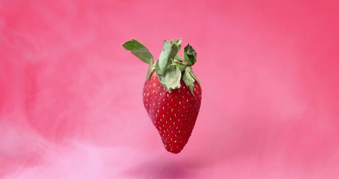 Red ripe strawberry floating on red background smoke vape mist flowing motion