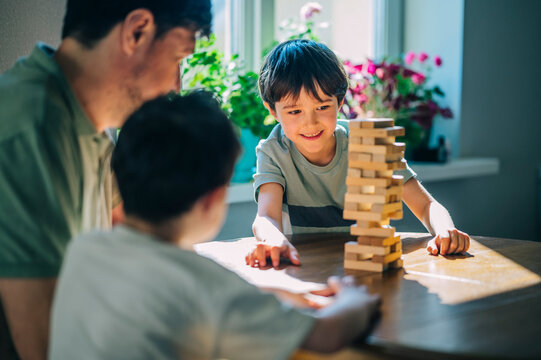 Smiling family playing a wooden block game together at home