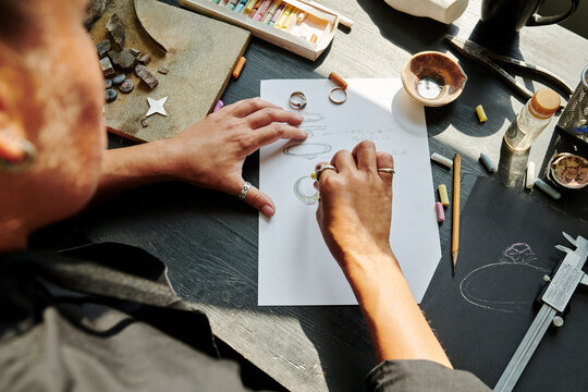 Jeweller sketching ring design on paper at workbench