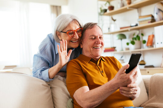 Happy senior couple on video call through smart phone at home