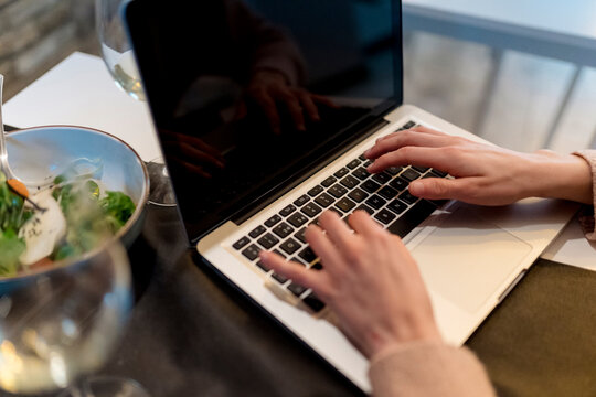 Woman using laptop at restaurant table
