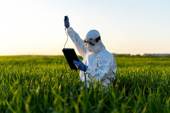 Female scientist researching in field and using measuring device