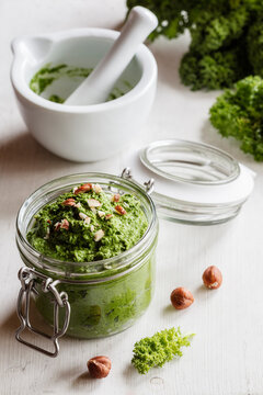 Preserving jar of vegan kale pesto with hazelnuts