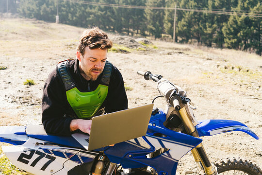 Portrait of motocross driver using laptop