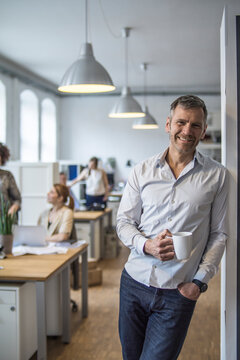 Smiling man in office with colleagues in background