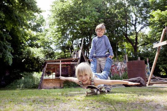 Boy pushes a child on a skateboard at an adventure playground