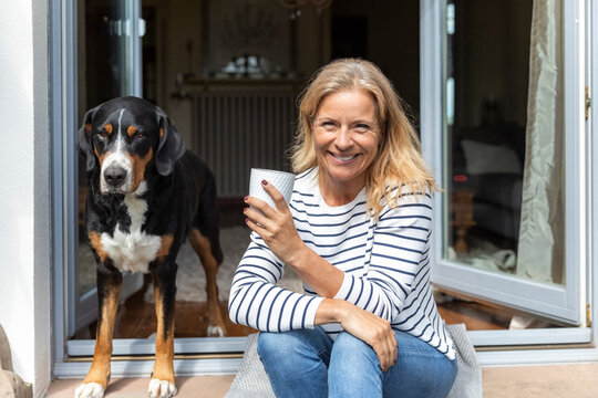 Portrait of happy mature woman sitting with coffee mug on terrace