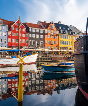 Denmark, Copenhagen, Boats moored along Nyhavn promenade with row of historical townhouses in background