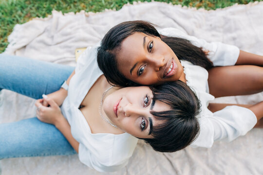 Lesbian couple sitting back to back on blanket