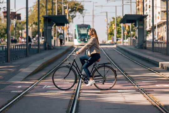 Woman rides a bike across tram tracks in the city