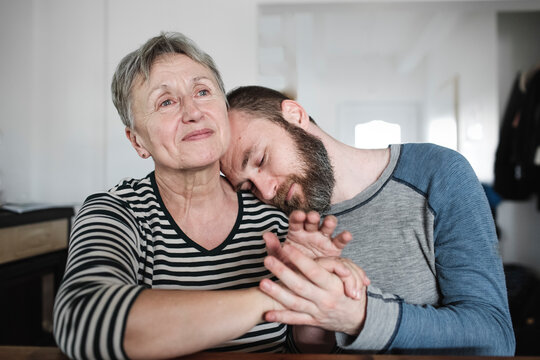 Affectionate adult son with senior mother at home