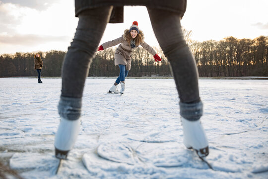 Woman ice skating on frozen lake with friends