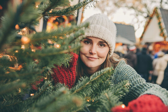 Woman looking trough conifer branches on the Christmas Market