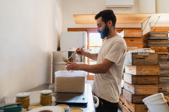 Male beekeeper fills a jar with natural pollen at the apiary