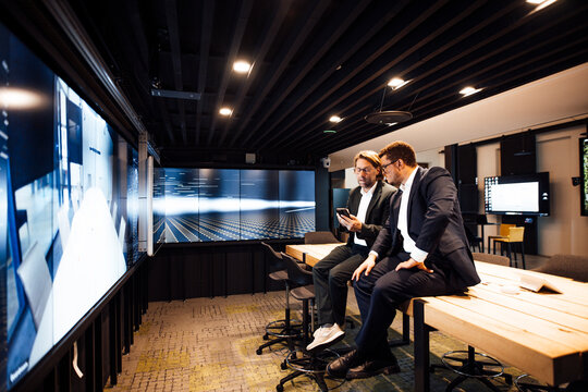Businessmen read news on a smartphone inside a tv studio