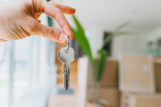 A hand holds a key to a new apartment during a moving day