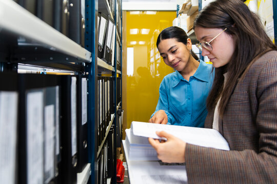 Businesswomen read a document together in an office archive