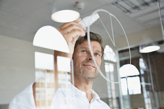 Businessman drawing diagram on glass pane in office