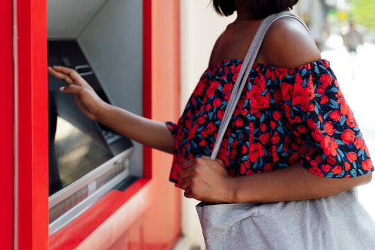 Woman with shoulder bag using ATM