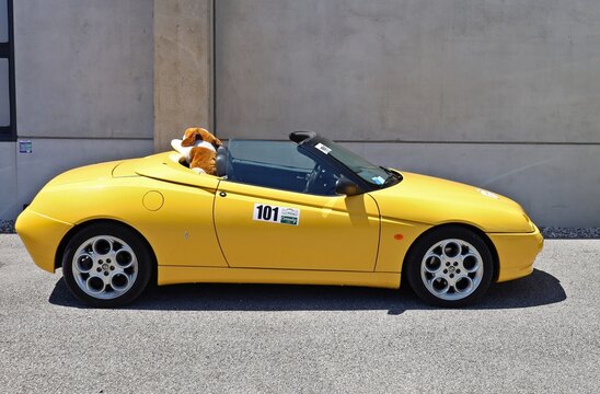 Azzida, Italy. July 4 2026. Side view of yellow Alfa Romeo Spider 916, nineties convertible sports car of the italian automaker, during a classic car rally.