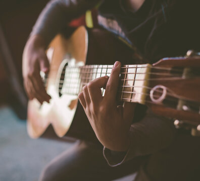 Little boy playing acoustic guitar at home, close-up