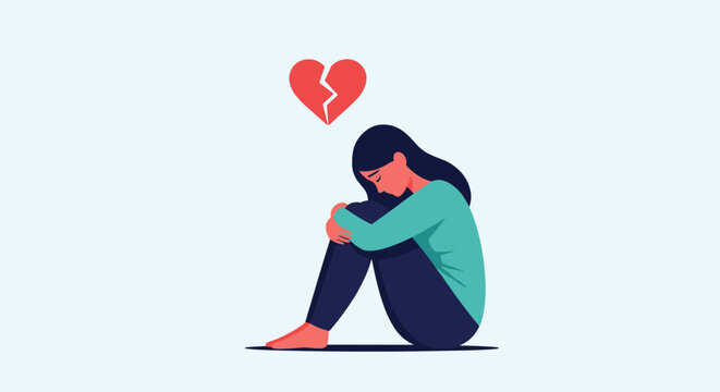 Sad heartbroken young woman sitting on the floor and hugging her knees with red broken heart symbol above her.