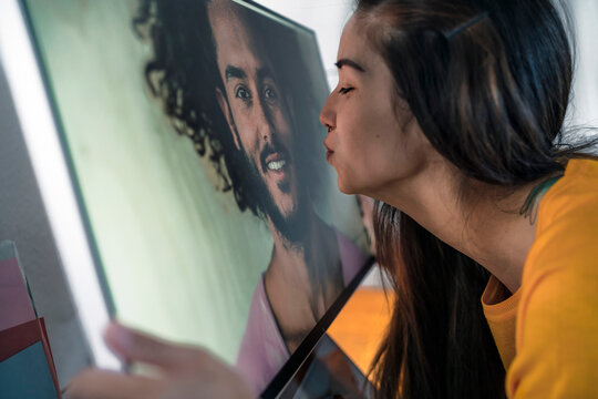 Young woman kissing man on computer screen