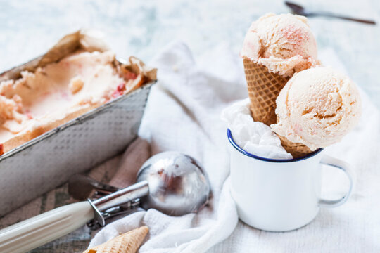 Vanilla icecream with fruit swirl in loaf pan, emaille cup with ice-cream cone and ice scoops, ice cream scoop
