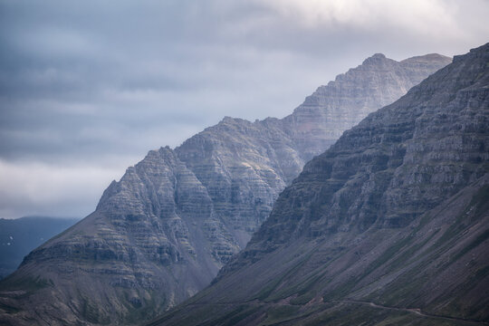 Ancient basalt mountains rise under a cloudy sky in Iceland