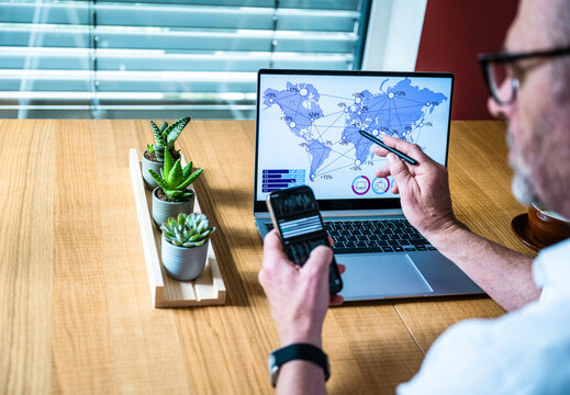 Businessman analyzes global data on notebook and mobile phone