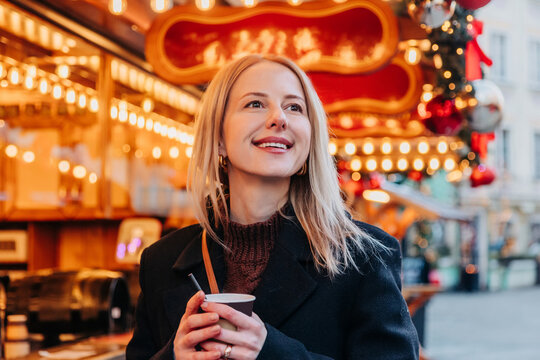 Smiling woman drinks takeaway coffee at a European Christmas market