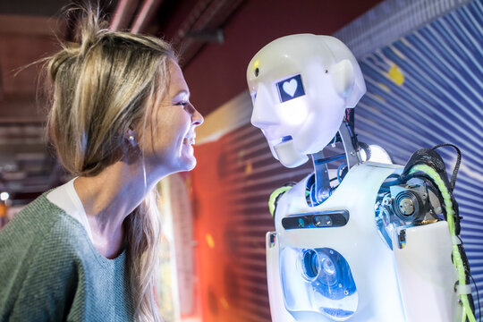 Tech developer smiling in front of human robot at workshop