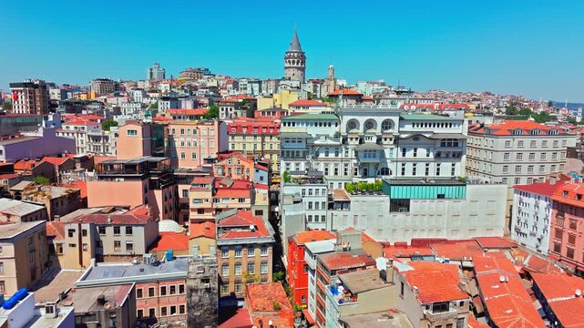 Drone view of Galata Tower and the Golden Horn in Istanbul. The historic tower stands above waterfront buildings, rooftops and busy city streets.