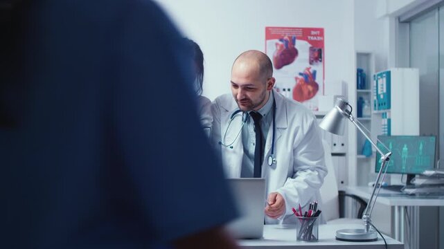Male and female doctor practitioners consult each other about a patient problem in a modern private hospital clinic focused on treatment planning.