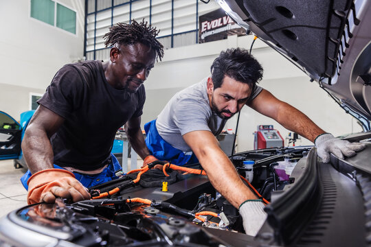 Professional EV technicians collaborating to diagnose and resolve an electrical problem in a modern electric vehicle service workshop.