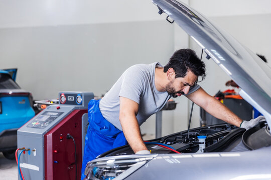 Professional Technician Inspecting Electric Vehicle During Routine Maintenance in Modern EV Service Center