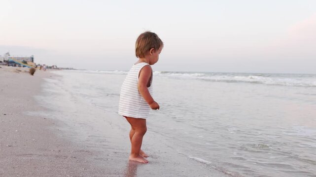 Kid collects shells and pebbles in the sea on a sandy bottom under the summer sun on a vacation