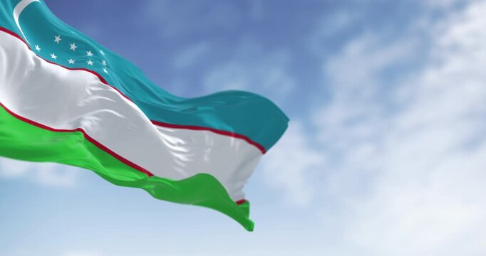 Three national flags of Uzbekistan waving on a clear day.