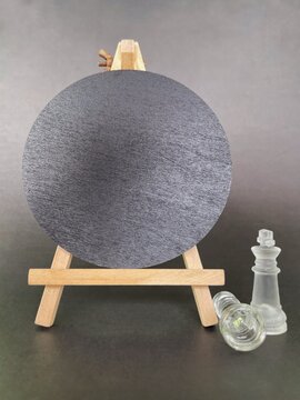 Blank round black sign on wooden easel with transparent chess pieces for business strategy and branding concept