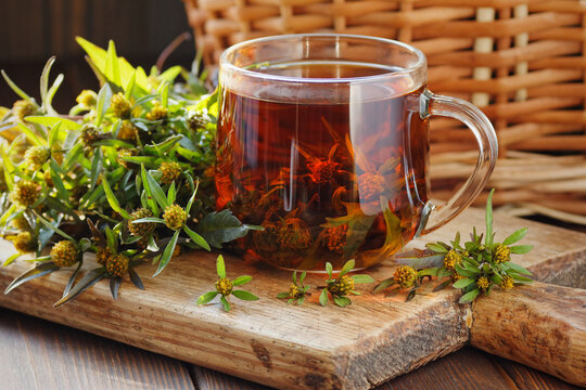 Healthy bidens herbal tea in a glass cup, natural bio retinol source and antibacterial treatment on wood