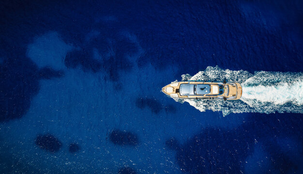 Aerial overhead view of a modern luxury yacht sailing over the turquoise ocean with copy space