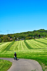 Obraz premium Kind mit Fahrradhelm fährt auf einem Feldweg an einer gemähten Wiese vorbei in Breitenborn, Main-Kinzig-Kreis, Hessen
