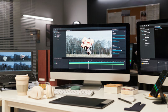 Close up of video editing workstation displaying explosion footage on desktop monitors and laptop, supporting post production workflow. Ideal for media agency, visual effects marketing