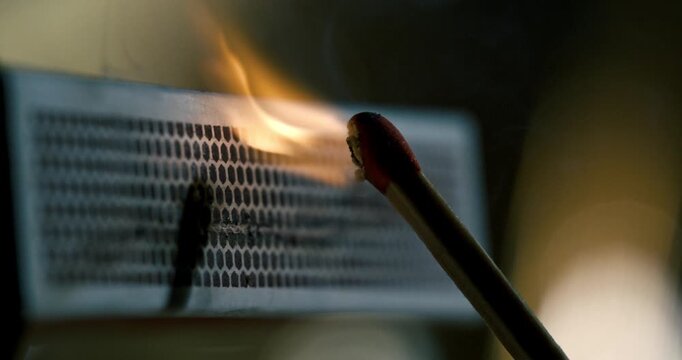  Close-up of a wooden match igniting against a matchbox striker in slow motion.