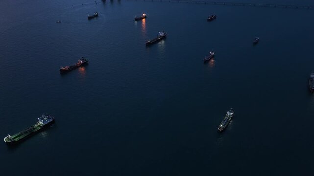  heavy oil tankers and LNG vessels anchored at a strategic maritime chokepoint during a golden sunset, emphasizing global energy crises and petroleum supply chain infrastructure.