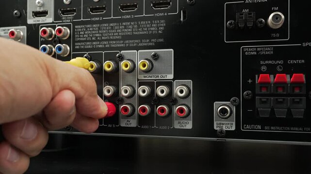 Male hand connects yellow and red RCA cables into the monitor out ports of an o video receiver, emphasizing analog connections and home entertainment setup.