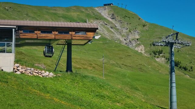 Geils-Hahnenmoos gondola arrives at the mountain station in Adelboden, Switzerland, surrounded by the scenic Bernese Oberland and lush alpine meadows on a summer day