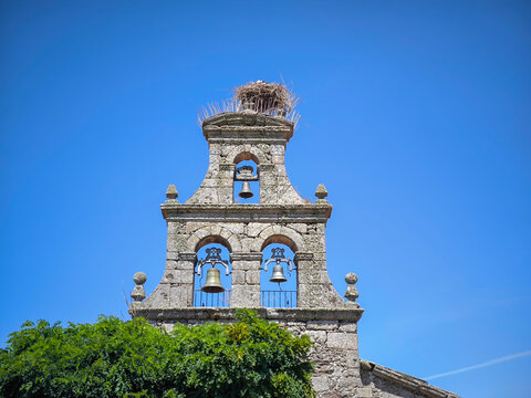 Torre sineira em estilo de espigueiro da Igreja do Sant&iacute;ssimo Cristo del Campo em San Vitero, Espanha, com um ninho de cegonha sob c&eacute;u azul