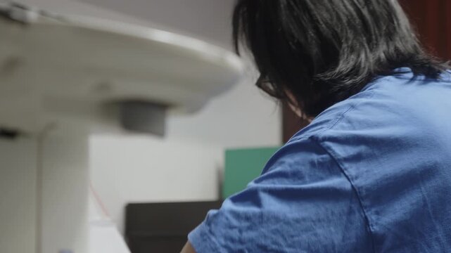 Rack focus shifts from a multifunction office printer to a healthcare administrator working at a desk, illustrating administrative workflow in a modern medical office.