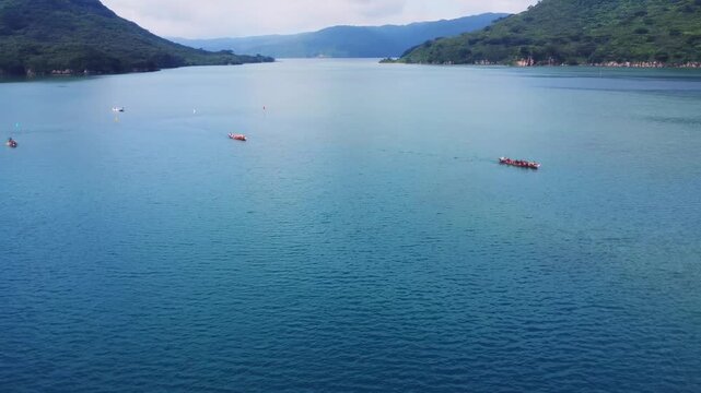 Aerial Drone View of Traditional Boat Race on Crystal Clear Blue Ocean with Mountain Landscape